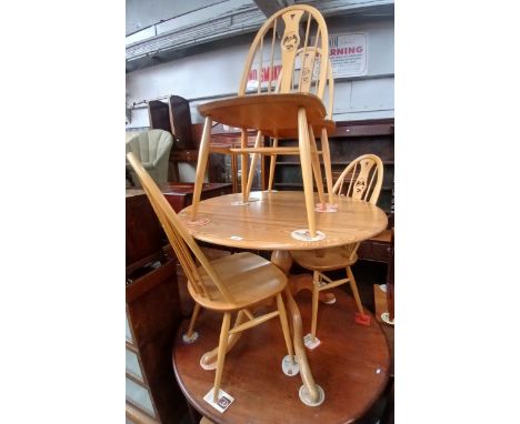 An Ercol light elm and beech oval extending pedestal table with four swan back chairs. 