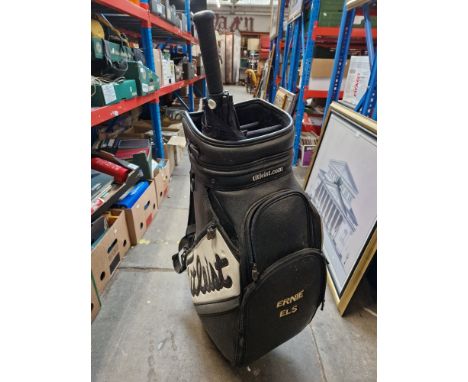 A Titleist golf bag with Ernie Els embroidered on the side with a Taylor made golf umbrella.