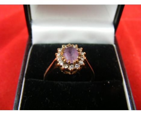 A 9ct gold Ring, with a central stone surrounded by small Diamonds,