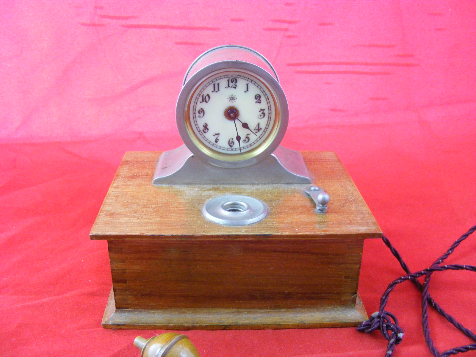 A mechanical Bedside Clock, mounted on wooden plinth, labelled