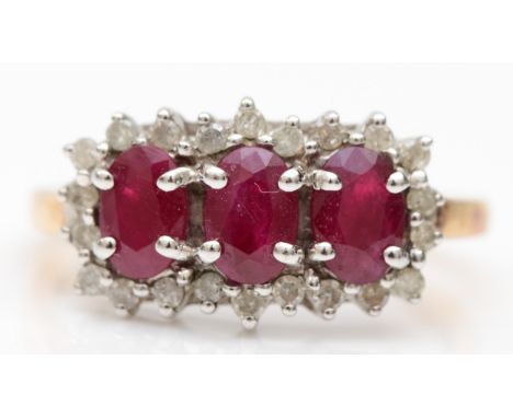 A 9ct gold three stone ruby dress ring, with eight cut diamond surround, P-Q, 3.2gm. 