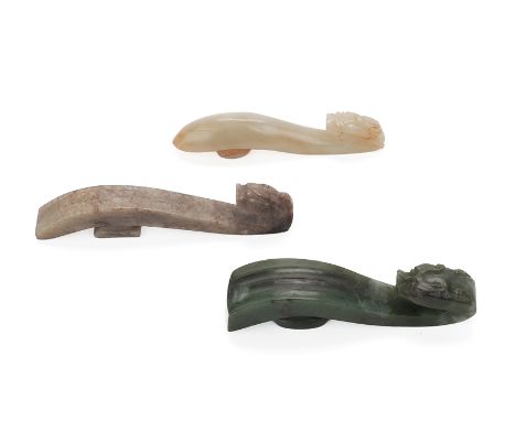 A GROUP OF THREE JADE BELT HOOKS
Each with dragon head terminal, including one of mottled green colour, and two of celadon an