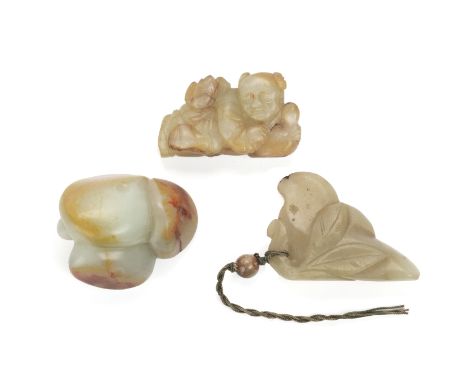 A GROUP OF THREE JADE CARVINGS
Comprising: a russet included carving of a boy holding a a lotus flower; a celadon and russet 