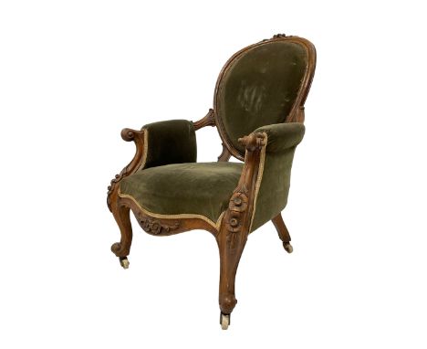 Victorian walnut open armchair, the cresting rail carved with flower heads and extending foliage, oval back with moulded fram
