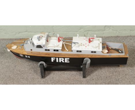 A remote control kit built model fire rescue boat, number 94, on display stand. Includes components for working fire hoses. A