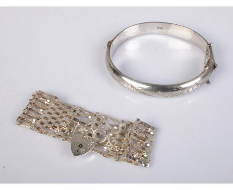 A silver tulip engraved bangle along with silver gate bracelet with heart lock. Total weight 31.5g.  