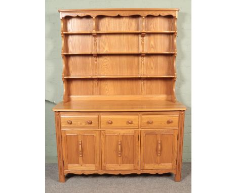 An Ercol light oak Welsh dresser, with cupboard doors and drawers to the base and plate rack top. Height: 191cm, Width: 146cm