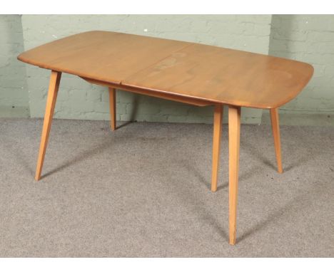 An Ercol 'Grand Windsor' light oak and ash extending dining table, with hinged additional leaf, rounded D-ends and raised on 