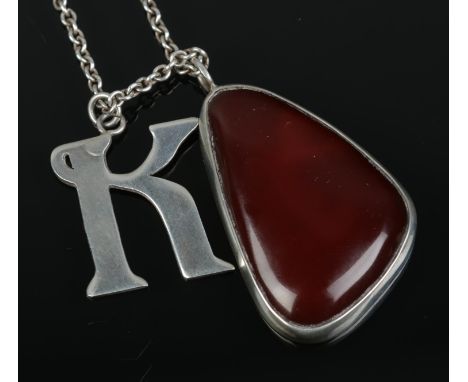 A silver mounted carnelian pendant and silver K pendant on chain.  