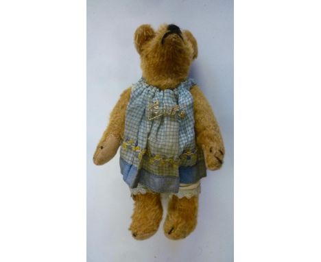 A small teddy bear, pre-war, covered in dark gold plush, swivel joints and felt pads, button eyes, 7" high, wearing a blue ch