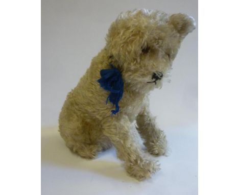 A Steiff seated dog, mid 20th century, straw filled, covered in cream plush, swivel head, black/amber eyes, (one) ear with me