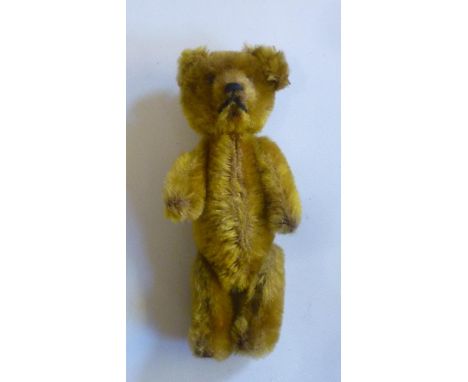 A Continental miniature teddy bear, early 20th century, possibly Schuco, with swivel head and limbs, covered in gold plush, b