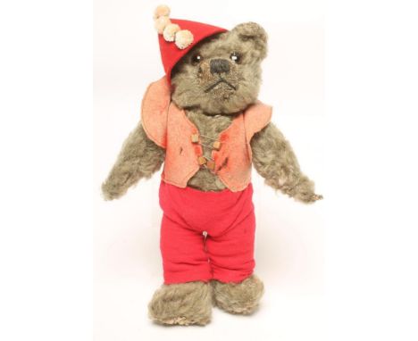 A Chiltern teddy bear covered in grey plush with swivel joints, amber/black glass eyes, wearing a red felt clown's costume, 1