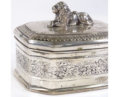 An octagonal white metal hinged box, with cast reclining lion finial and engraved foliate border, length 9cm, 6.7oz 