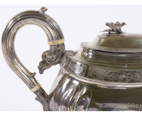 A George III oval silver teapot, with applied flower finial, bright-cut floral frieze and foliate feet, with ivory insulators