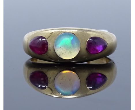 An 18ct gold 3-stone opal and star ruby ring, set with cabochon white opal, flanked by two cabochon pear cut star ruby should