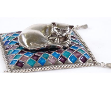 A modern Sarah Jones silver model of a cat on a coloured enamel cushion, with hanging corner tassels and brushed effect under