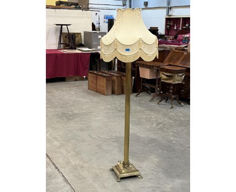 A brass lamp standard with gold tasselled shade.