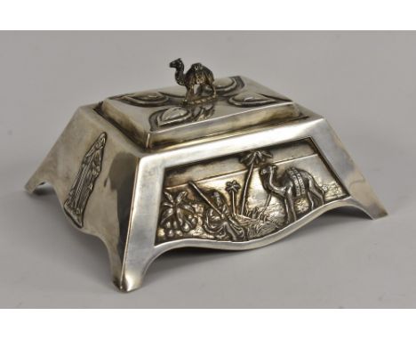 An unusual silver table box, the angular sides embossed with various panels, Nile scene with palm trees and camel, Saintly fi