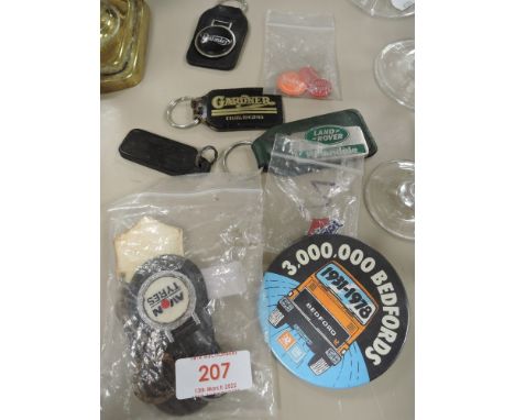 A selection of collectable automobile badges and keyrings including Land rover and Daimler.