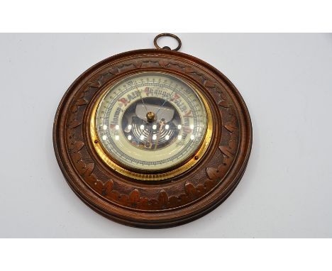 A circular brass cased barometer mounted on hardwood base.