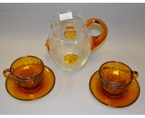 A set of six amber-glass tea cups with saucers and a clear water pitcher with amber glass detail and a set of 6 tumblers