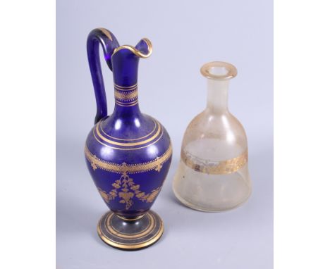 A 19th century blue glass ewer with tooled gilt decoration, 12" high, and a clear bell shaped decanter with tooled gilt band