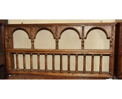 A carved oak wall shelf with arcaded top and spindles, 42" wide