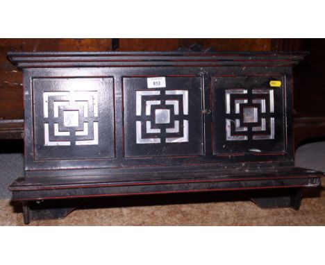 A Victorian ebonised and red decorated wall bracket with pierced and mirror panelled back, 24" wide