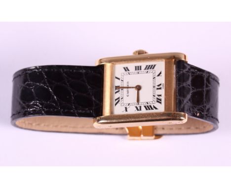 A gentleman's 18ct gold cased Cartier Tank wristwatch with white enamel dial and Roman numerals, sapphire crown, on black cro