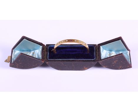A Victorian yellow metal hinged bangle set single ruby and seed pearls, 11.2g, in fitted case