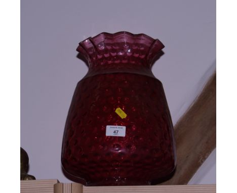 A dimpled ruby glass oil lamp shade and a number of other coloured glass shades