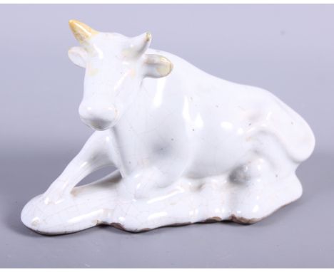 An 18th century Delftware model of a recumbent cow, 6" long (horn restored)