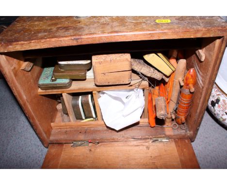 A wooden cabinet with brass carrying handle and drop down door containing assorted fishing paraphernalia including a Hardy me