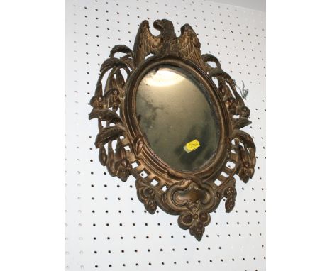 An oval wall mirror, in cast gilt metal frame with eagle surmount, 15" x 11" overall, and an oval bevelled wall mirror, in gi