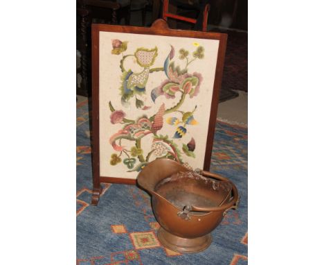 A copper coal helmet and an embroidered firescreen, in mahogany frame