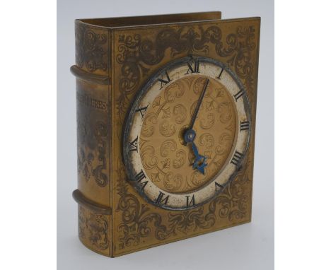 A mid 20th century gilded metal book clock made by Angelus, the front of the book engraved with scrolling foliate designs, th