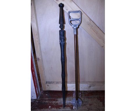 A vintage metal shooting stick and a hand carved African themed wooden walking stick, shipping unavailable 