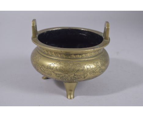 A CHINESE ENGRAVED BRASS TRIPOD CENSER, the base with character mark, 11.5cm wide.