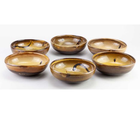 † SID TUSTIN (1914-2005) for Winchcombe Pottery; a set of six slipware bowls covered in yellow galena glaze with different ir