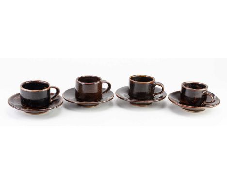 † EMMANUEL COOPER (1938-2012); a set of four stoneware coffee cups and saucers covered in tenmoku breaking to kaki glaze, imp