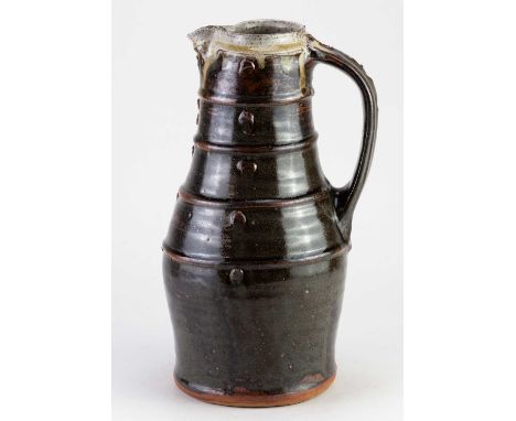 JIM MALONE (born 1946); a tall stoneware pitcher covered in tenmoku breaking to kaki glaze with grey/green ash rim, impressed