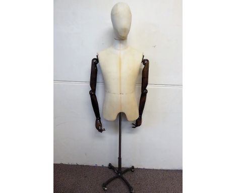 A Fabric Mannequin Male Torso with articulated wooden arms, the mannequin on metal support with casters, approx 175 cms tall.