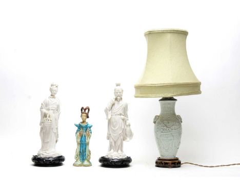 A pair of Chinese blanc de chine figures, each raised on a carved ebonised wood base; together with a Chinese ceramic table l