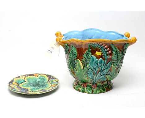A Majolica planter, decorated with ferns and flowering foliage on a brown ground, 24.5cms high; together with a Majolica leaf