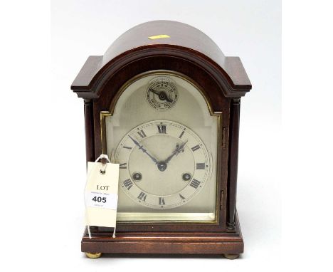 A mahogany dome cased mantle clock, raised on four brass bun feet, 25.5cms high. 