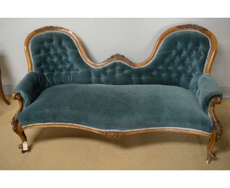 An attractive Victorian carved walnut two seat button-back sofa, the undulating back decorated with flowers and leaves, serpe