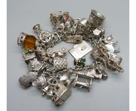 A silver bracelet with over 30 silver and white metal charms, 132g 