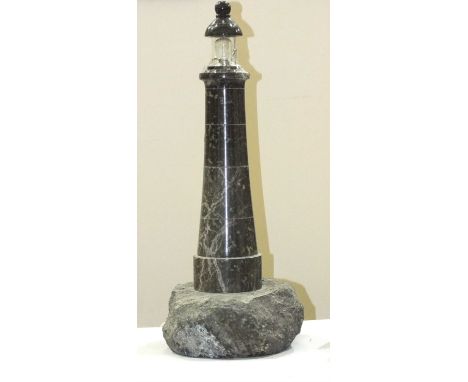 A large Cornish serpentine novelty table lamp in the form of a lighthouse, with transparent glass shade, (damaged), on a rock