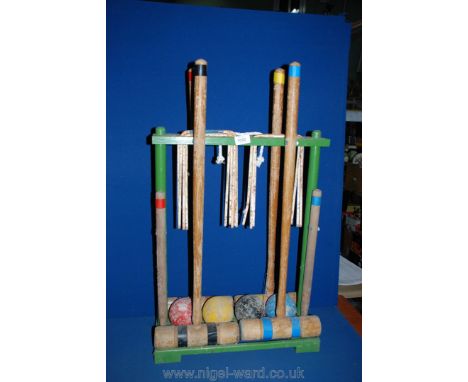 A vintage child's Croquet set on wooden stand, with four mallets, four balls and metal hoops